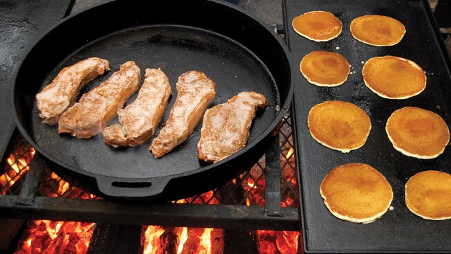 Steaks and pancakes cook over an open fire