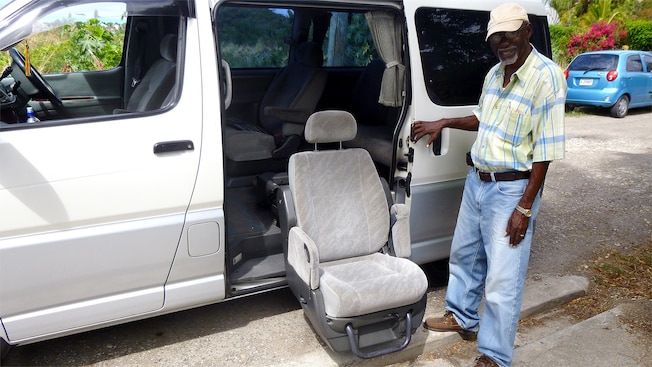 A guide poses next to a retractable chair, which is extended from the open side door of a van A guide poses next to a retractable chair, which is extended from the open side door of a van
