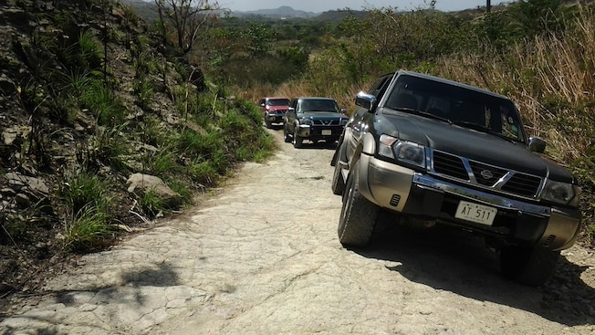 Três SUVs dirigem em uma estrada seca em meio a mato seco Três SUVs dirigem em uma estrada seca em meio a mato seco