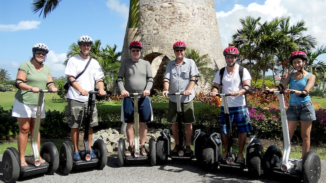 4 adults and 2 teenagers pose together wearing safety gear on Segway PTs