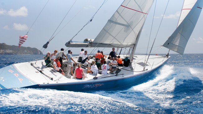 Passengers smile and enjoy the sea air as their sailboat races on the waves of the ocean