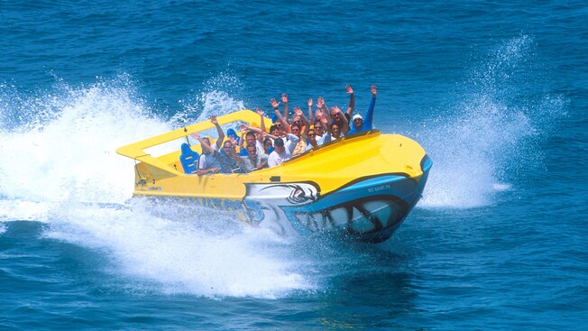 Water splashes in the wake of a high powered speedboat filled with passengers
