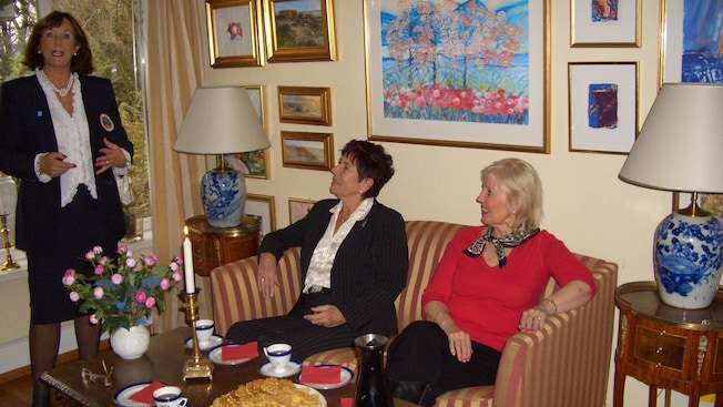 2 women sit at a coffee table with waffles on it, listening to another woman talking 2 women sit at a coffee table with waffles on it, listening to another woman talking