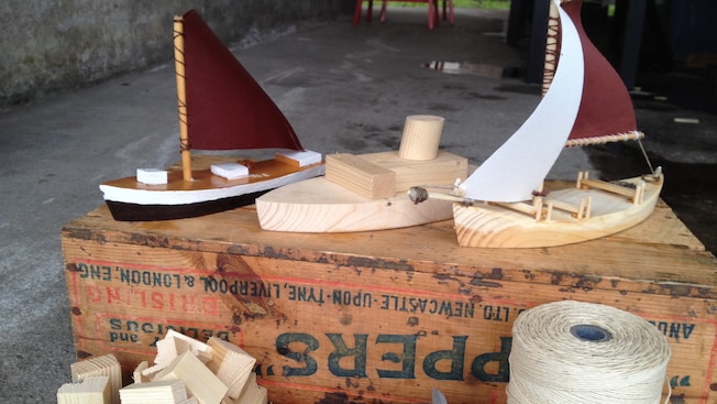 3 model boats in various stages of completion sit on a wooden box next to model building materials 3 model boats in various stages of completion sit on a wooden box next to model building materials