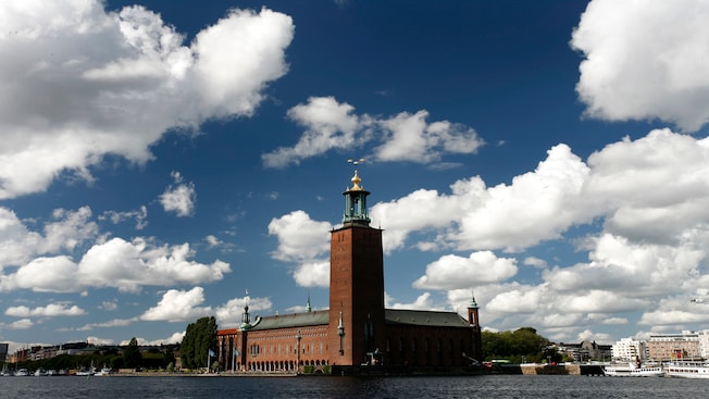 A building topped with a golden spire near a body of water A building topped with a golden spire near a body of water