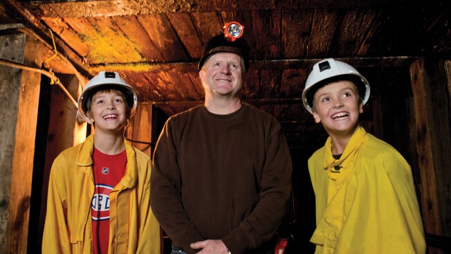 A man and young boys smiling inside a mine shaft