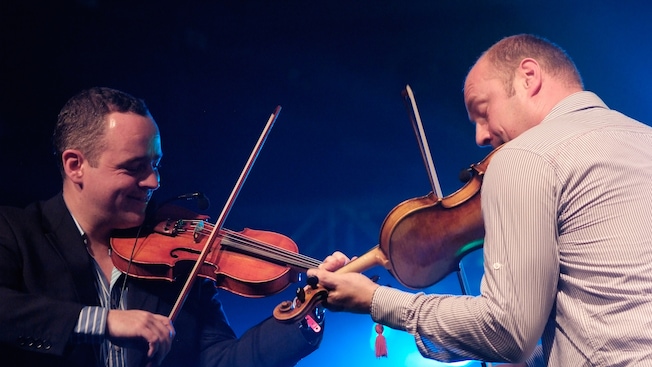 Men facing each other while playing violins Men facing each other while playing violins