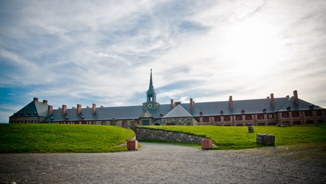 A gravel pathway leading to a building with windows and chimneys A gravel pathway leading to a building with windows and chimneys
