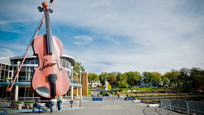 A huge violin sculpture on the Sydney waterfront next to a cruise ship terminal building A huge violin sculpture on the Sydney waterfront next to a cruise ship terminal building