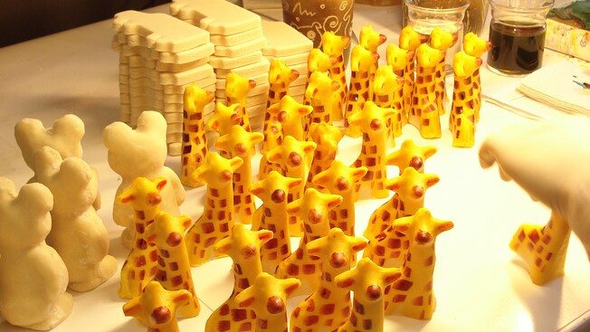 A cluster of candy giraffes next to unfinished white chocolate pieces on a table