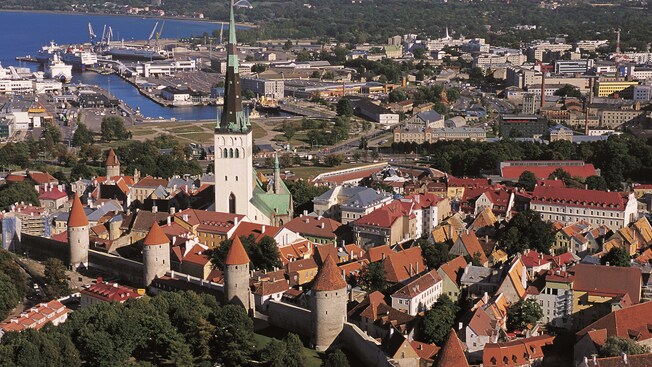 A medieval wall borders an old seaside town from a forested area