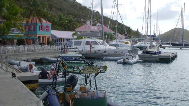A marina filled with boats of various sizes and a boardwalk lined with charming shops and cottages