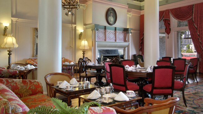 Uma sala de estar em estilo colonial com 2 enormes colunas centrais está preparada para o chá da tarde