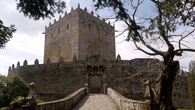 A cobblestone bridge leads to the iron front door of a square medieval castle A cobblestone bridge leads to the iron front door of a square medieval castle