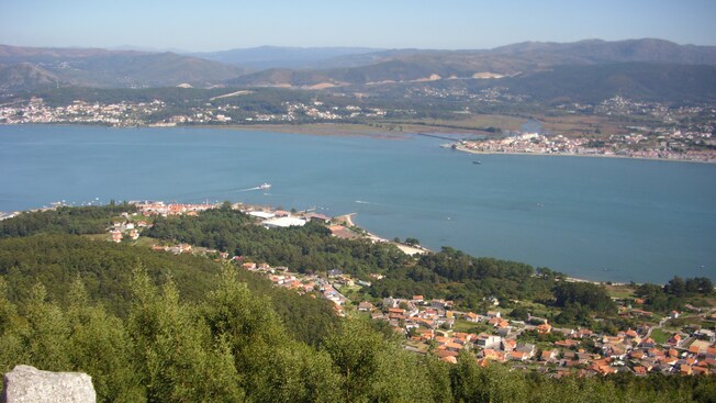 La vista desde una ladera de un pueblo en la costa de una bahía, con otros pueblos en el otro extremo de la bahía