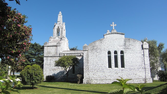 A church built of circular stones with a single steeple and three windows on the wall A church built of circular stones with a single steeple and three windows on the wall