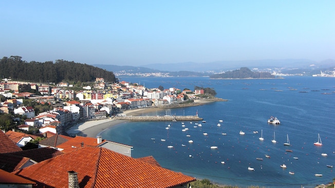 Una mezcla de construcciones grandes y pequeñas que cubren la costa junto a una ensenada con embarcaciones Una mezcla de construcciones grandes y pequeñas que cubren la costa junto a una ensenada con embarcaciones
