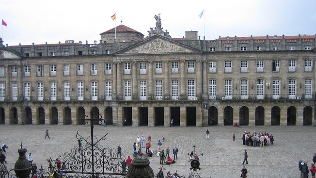 Edifício amplo de quatro andares com arcos de pedra ao longo do andar inferior e um telhado triangular
