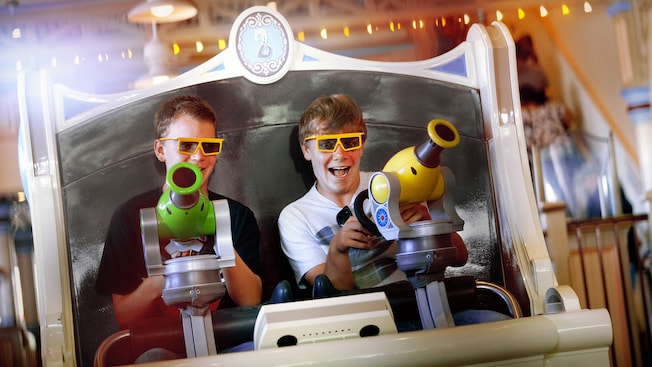 Dos Visitantes sosteniendo sus lanzadores mientras disfrutan de la atracción Toy Story Midway Mania en Disney California Adventure Park