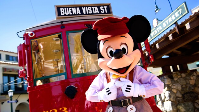 Mickey Mouse standing in front of a Red Car Trolley on Buena Vista Street