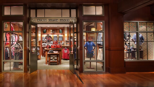 A shop accented with hardwood, a sign that reads 'Acorns Gifts & Goods' and merchandise that includes Disney-themed shirts, handbags, hats and Mickey Mouse ear hats