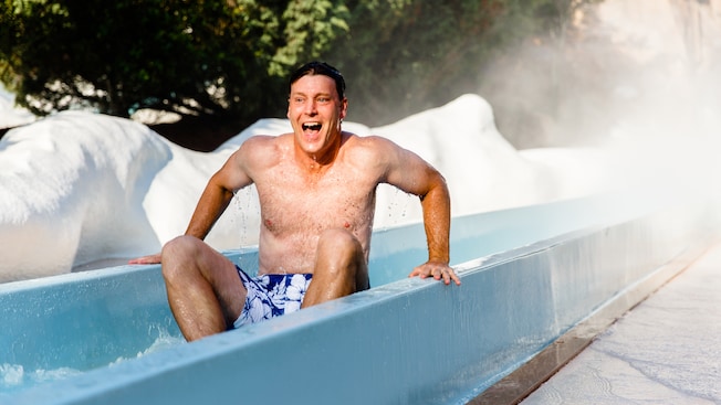 A Guest with a look of exhilaration slides to a stop at the end of waterslide
