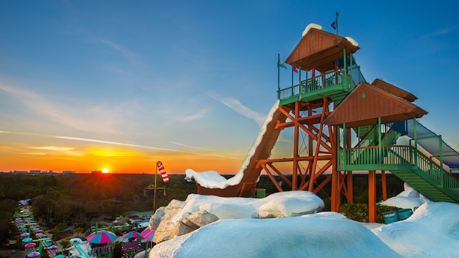 The morning sun peeks over the horizon, illuminating Summit Plummet attraction