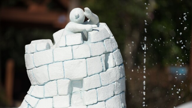 A small sculpture of a snowman pointing while standing in a ice-cube turret