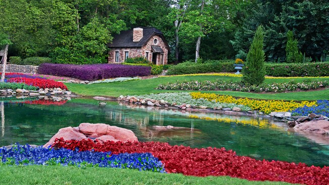 O Victoria Gardens com flores coloridas, um lago e uma pequena casa de pedra no Pavilhão do Canadá