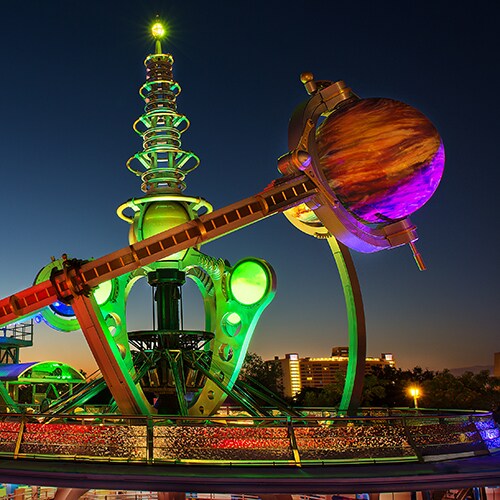 La futurística y colorida atracción Astro Orbiter iluminada de noche en Tomorrowland