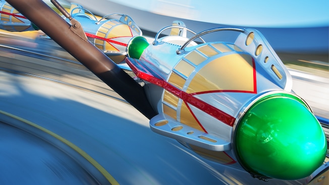 Rocket ships, held on by a metal arm, spin around a stylized tower at Astro Orbiter