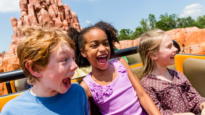 Três crianças gritam felizes enquanto passeiam na Big Thunder Mountain Railroad no Magic Kingdom Park