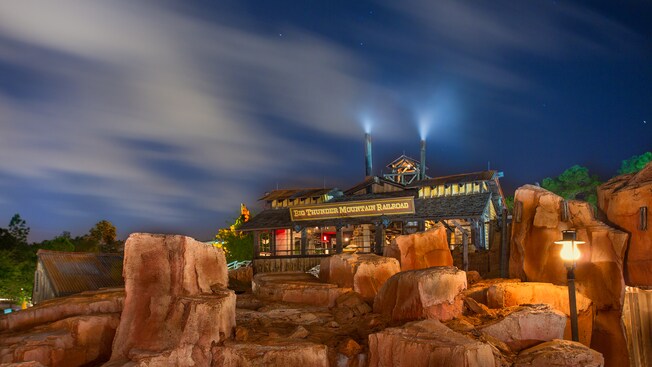 Edifício da estação rodeado por rochas na Big Thunder Mountain Railroad à noite