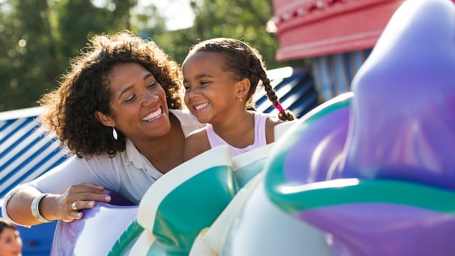 A mother and daughter giggle as they ride on Dumbo the Flying Elephant at Magic Kingdom park