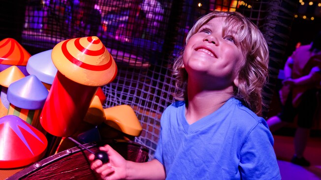 A boy looks up with delight while in the wait area for Dumbo the Flying Elephant attraction