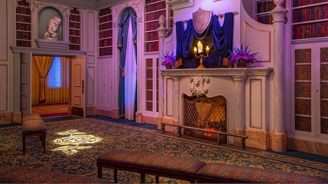 The candlelit Beast's library with a glowing fire in the fireplace at Enchanted Tales with Belle