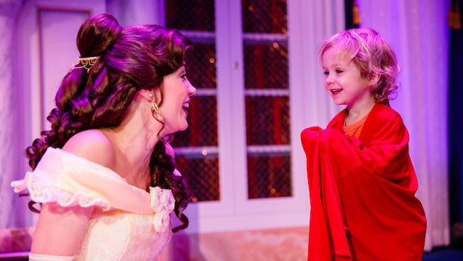 Belle tells a story to a toddler in the Beast's Library at Enchanted Tales with Belle
