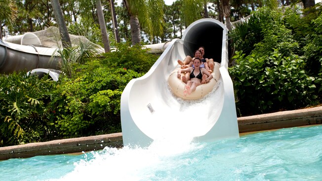 Three girls, sharing a raft, slide down Crush 'n' Gusher, about to splash down in Hideaway Bay