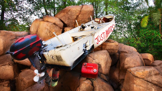 A boat with an outboard engine and a Just Married sign sits atop boulders at Storm Slides