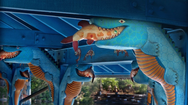 A wood sculpture of an alligator eating a fish on the rafters of a dining-patio roof