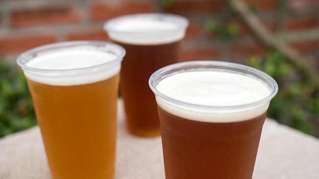 Un trío de vasos helados, cada uno lleno hasta el borde con distintas cervezas de barril