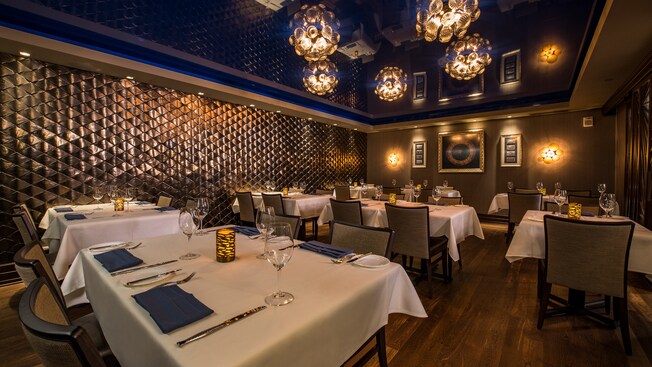 A tufted wall and chandeliers add a sophisticated backdrop to the impeccably set dining tables