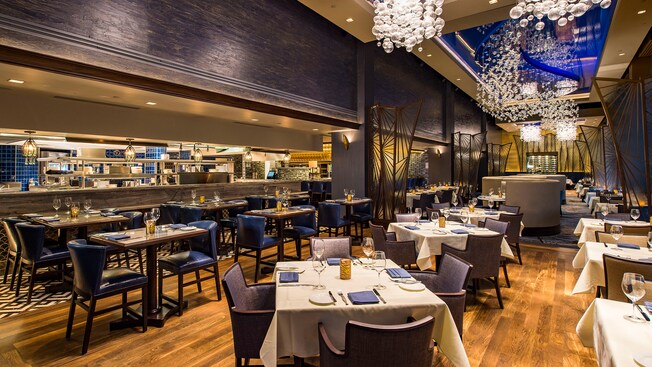 The brightly lit dining and bar areas feature modern furnishings and views of the open kitchen