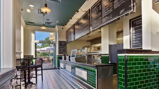Service counter with emerald-green wall tiles across from bar tables and chairs