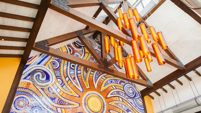 Cylinder lights dangling from ceiling beams in front of a vibrant wall mural