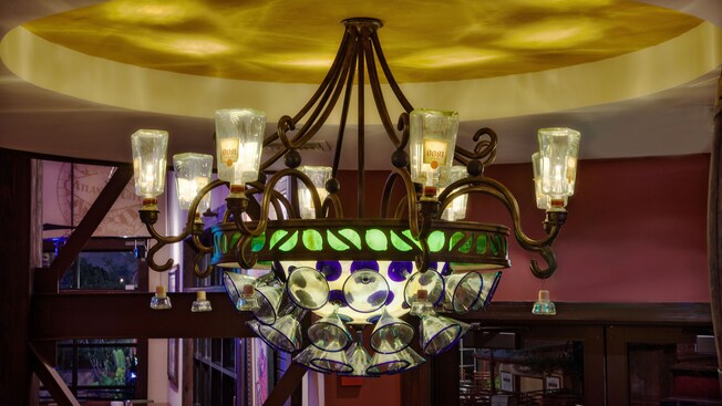 Vodka bottles, margarita glasses and green cut glass adorn a chandelier with brass fittings