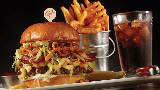 Una hamburguesa grande de carne de ternera y macarrones con queso, servida con papas fritas y un refresco