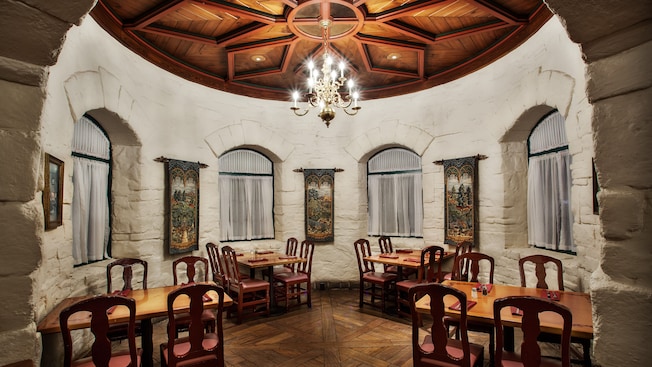 Dining alcove with whitewashed brick walls, wood-beamed floor and chandelier