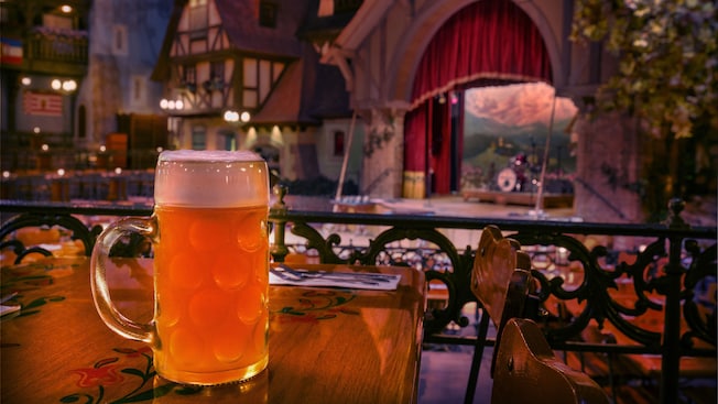 Close-up of a glass stein filled with beer and, in the background, a stage for entertainment