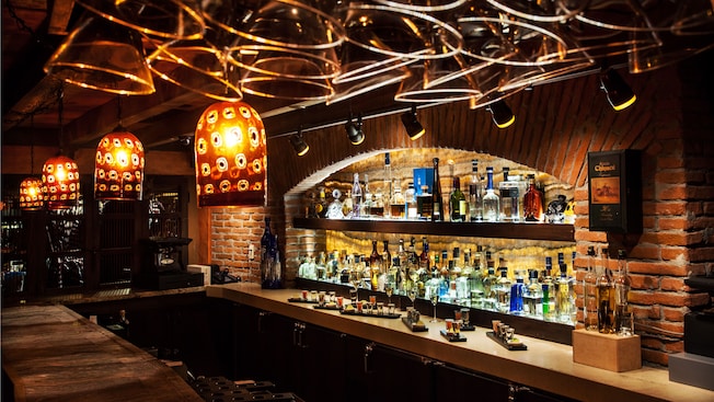 Liquor bottles on shelves inside a brick alcove with overhead lights